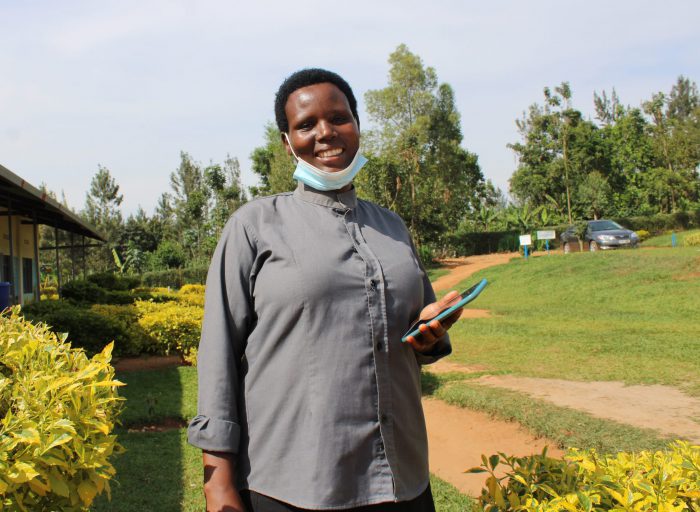 A Rwandan lady smiling and holding her phone